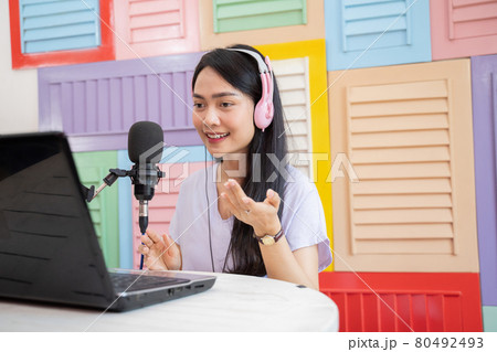 woman wearing headphones talking in front of microphone with hand gesture 80492493