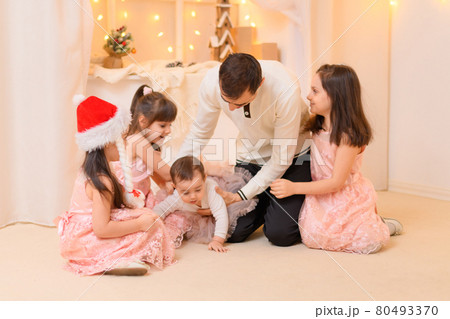 family portrait of a father and children in home interior decorated with lights 80493370