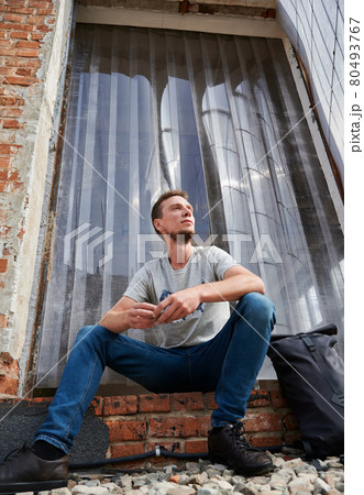 Smiling male is sitting on stairs outdoors. Smiling male is sitting on stairs outdoors. 80493767