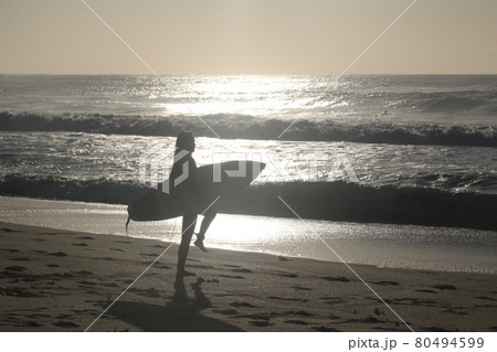 海の陽の光に映るサーファーガールの写真素材