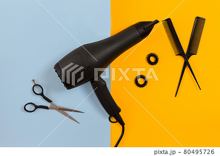Styling hair with scissors, dryer and tools in barbershop on blue and yellow paper background top view mock-up 80495726