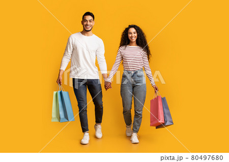Portrait Of Happy Middle Eastern Couple Walking With Bright Shopping Bags Portrait Of Happy Middle Eastern Couple Walking With Bright Shopping Bags 80497680