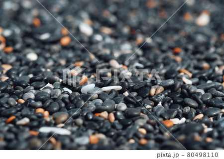 Abstract background with black and orange round sea pebble stones texture on the shore close up in the blurry sunset light, close up, natural copy space . Abstract background with black and orange round sea pebble stones texture on the shore close up in the blurry sunset light, close up, natural copy space . 80498110