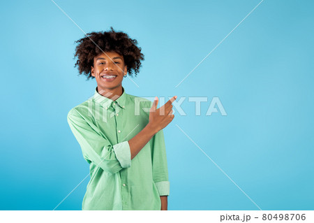 Special offer. Portrait of happy african american teen guy pointing at copy space, standing over blue background 80498706
