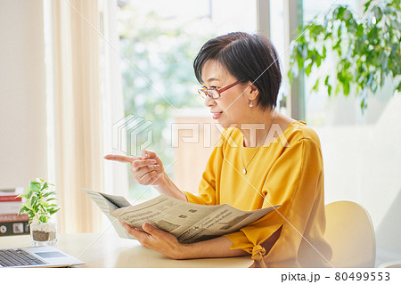 老眼鏡を掛けて英字新聞を読むミドル女性 老眼鏡を掛けて英字新聞を読むミドル女性 80499553