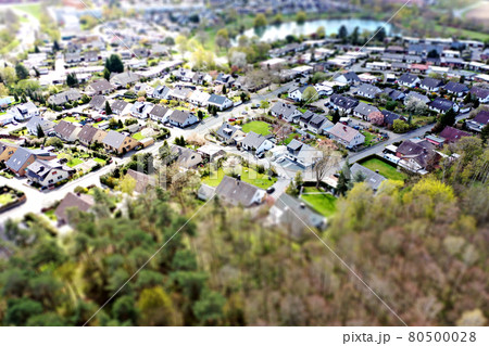 Aerial view of a housing estate on the outskirts of the big city Wolfsburg in Germany with a forest in the foreground, blurred by tilt shift effect 80500028