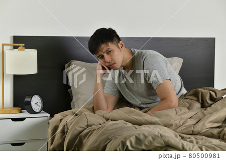 Depressed young Asian man sitting in bed cannot sleep from insomnia Depressed young Asian man sitting in bed cannot sleep from insomnia 80500981