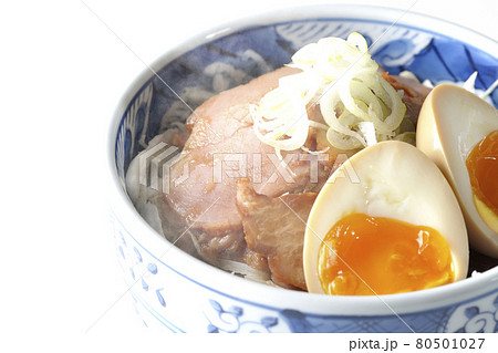 キャベツの千切りに味玉、ネギがトッピングされた湯気が立っている焼豚丼を白背景で撮影 80501027