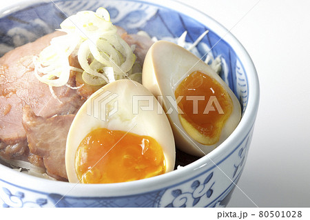 キャベツの千切りに味玉、ネギがトッピングされた湯気が立っている焼豚丼を白背景で撮影 80501028