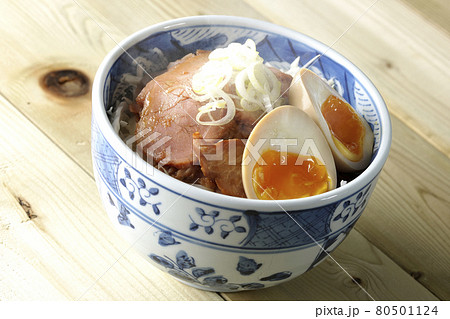 キャベツの千切りに味玉、ネギがトッピングされた湯気立つ焼豚丼 80501124