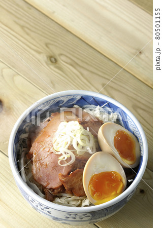キャベツの千切りに味玉、ネギがトッピングされた湯気立つ焼豚丼を俯瞰で撮影 80501155