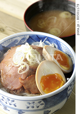 キャベツの千切りに味玉、ネギがトッピングされた湯気立つ焼豚丼と味噌汁のセット キャベツの千切りに味玉、ネギがトッピングされた湯気立つ焼豚丼と味噌汁のセット 80501179