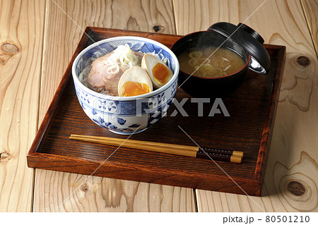 キャベツの千切りに味玉、ネギがトッピングされた湯気の立つ焼豚丼と味噌汁のセット 80501210