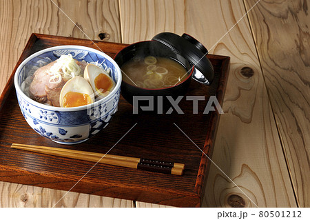 キャベツの千切りに味玉、ネギがトッピングされた湯気の立つ焼豚丼と味噌汁のセット キャベツの千切りに味玉、ネギがトッピングされた湯気の立つ焼豚丼と味噌汁のセット 80501212