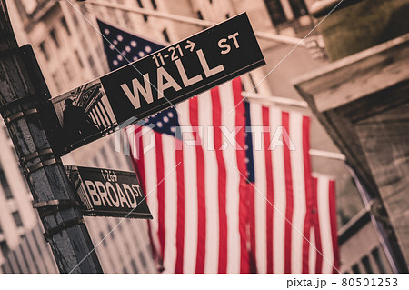 Wall street sign in New York with American flags and New York Stock Exchange in background 80501253