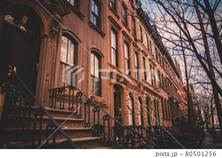 Row of old brownstone buildings along an empty sidewalk block in the Greenwich Village neighborhood of Manhattan, New York City NYC Row of old brownstone buildings along an empty sidewalk block in the Greenwich Village neighborhood of Manhattan, New York City NYC 80501256