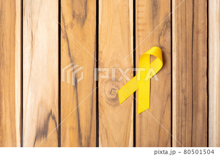 Yellow Ribbon on wooden table background for supporting people living and illness. September Suicide prevention day, Childhood Cancer Awareness month and World cancer day concept 80501504