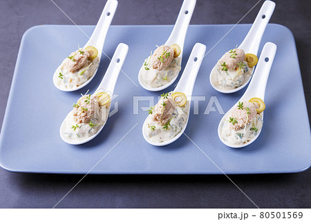 Cold appetizer made from cod liver, cod caviar, olives, cucumber and microgreens on serving spoons. Traditional cold dish. Close-up, blue plate, black background. Cold appetizer made from cod liver, cod caviar, olives, cucumber and microgreens on serving spoons. Traditional cold dish. Close-up, blue plate, black background. 80501569