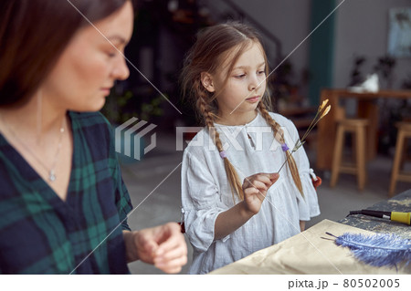 Flourist shop with different kinds of dryed flowers. Young happy confident specialist is working with her female kid. 80502005