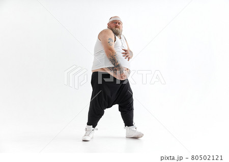 Happy fat man with big belly and tattoes in sports wear is holding his stomach 80502121