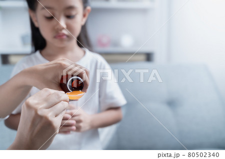 Mother is giving medicine to her sick daughter. 80502340