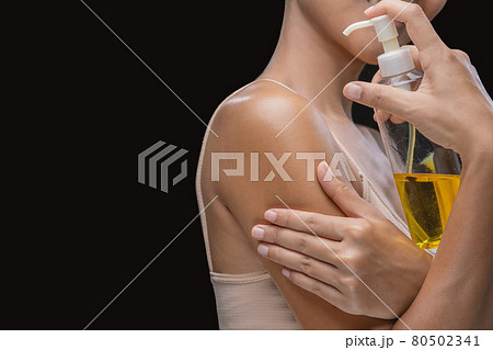 A woman is applying olive oil to her skin. 80502341
