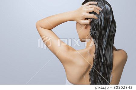 A woman is washing her hair and taking a shower. 80502342