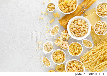 Pasta. Various kinds of uncooked pasta and noodles over stone background, top view with copy space for text. Italian food culinary concept. Collection of different raw pasta on cooking table Pasta. Various kinds of uncooked pasta and noodles over stone background, top view with copy space for text. Italian food culinary concept. Collection of different raw pasta on cooking table 80503131