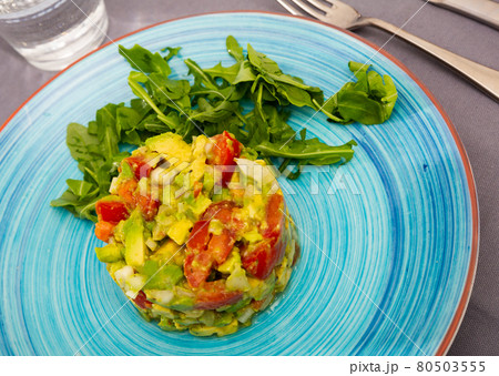 Tasty salad guacamole with red tomatoes and arugula at plate 80503555