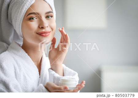 Beautiful woman with green eyes coming out of the bath with cream in her hands. 80503779