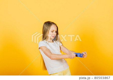 Young girl playing with blue slime on yellow background 80503867