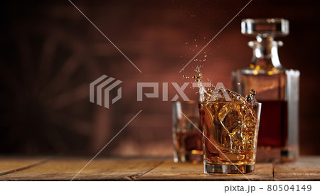 Freeze motion of ice cube falling into whisky shot Freeze motion of ice cube falling into whisky shot 80504149