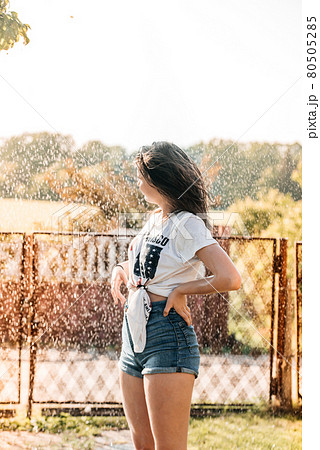girl with a fountain in the garden at sunset. hot summer, wet shirt. USA flag girl with a fountain in the garden at sunset. hot summer, wet shirt. USA flag 80505285