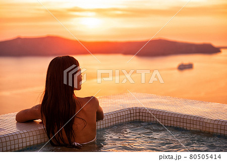 Luxury wellness spa resort pool woman relaxing in jacuzzi swimming at sunset in Europe Santorini hotel travel destination. Summer holiday. Luxury wellness spa resort pool woman relaxing in jacuzzi swimming at sunset in Europe Santorini hotel travel destination. Summer holiday. 80505414