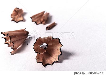 Macro detail closeup of wooden curly pencil shavings on white paper background - Concept of studying, school homework, planning, drawing or writing Macro detail closeup of wooden curly pencil shavings on white paper background - Concept of studying, school homework, planning, drawing or writing 80506244