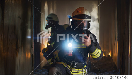 Firemen examining hallway after fire 80508140