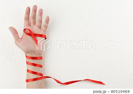Red cancer ribbon wrapped around the arm. 80510469