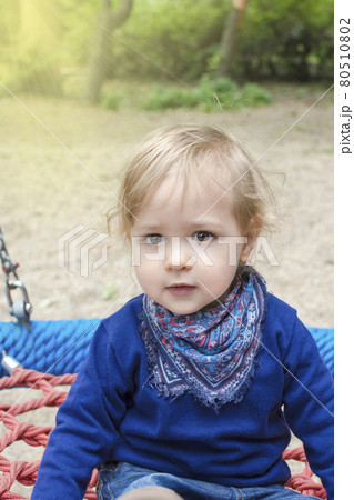 Cute little child having fun on a colorful swing outdoor in the park. Beautiful spring day in children playground Cute little child having fun on a colorful swing outdoor in the park. Beautiful spring day in children playground 80510802