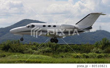 着陸直前に滑走路上空を通過する、双発のビジネスジェット 80510821
