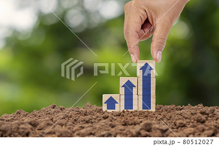hand holding wooden cube with arrow icon continually rising on the ground financial and business growth concept 80512027