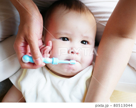 母親の膝の上で歯磨きを嫌がるハーフの赤ちゃん 80513044