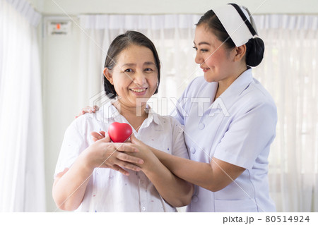 Nurse and Asian elderly woman holding heart red model on hands together,Senior healthy and taking care concept Nurse and Asian elderly woman holding heart red model on hands together,Senior healthy and taking care concept 80514924