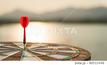 Soft focus shot red darts arrows in the target center on dark sky background. Business target or goal success and winner concept. Soft focus shot red darts arrows in the target center on dark sky background. Business target or goal success and winner concept. 80515446