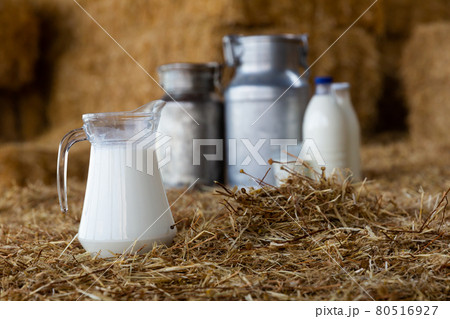 Jug, cans and glass with milk on hay stacks Jug, cans and glass with milk on hay stacks 80516927