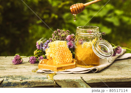 Fresh honey in a glass jar on a summer rural background. Floral fragrant sweet honey dessert, front view  80517114