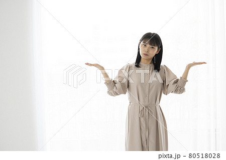 右手と左手の上のものを比べるようなジェスチャーの若い女性 80518028