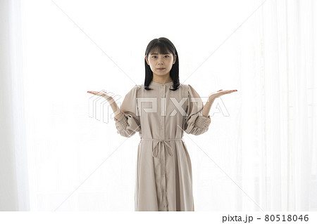 右手と左手の上のものを比べるようなジェスチャーの若い女性 80518046