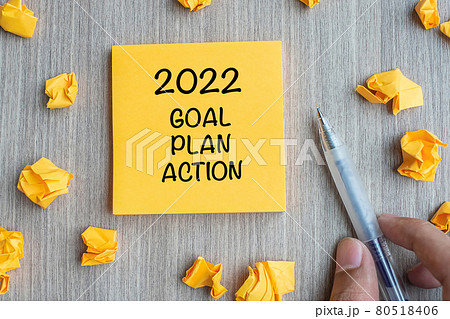 2022 Goal, Plan, Action word on yellow note with Businessman holding pen and crumbled paper on wooden table background. New Year New Start, Resolutions, Strategy  concept 80518406