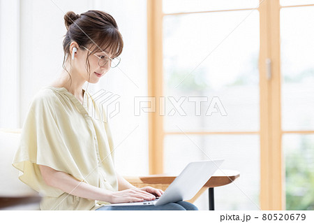 イヤホンを付けてパソコンを見る若い女性 イヤホンを付けてパソコンを見る若い女性 80520679
