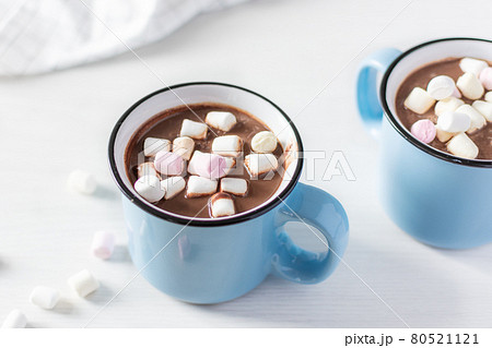 Hot chocolate with marshmallows in a blue enamel mug on white table. 80521121